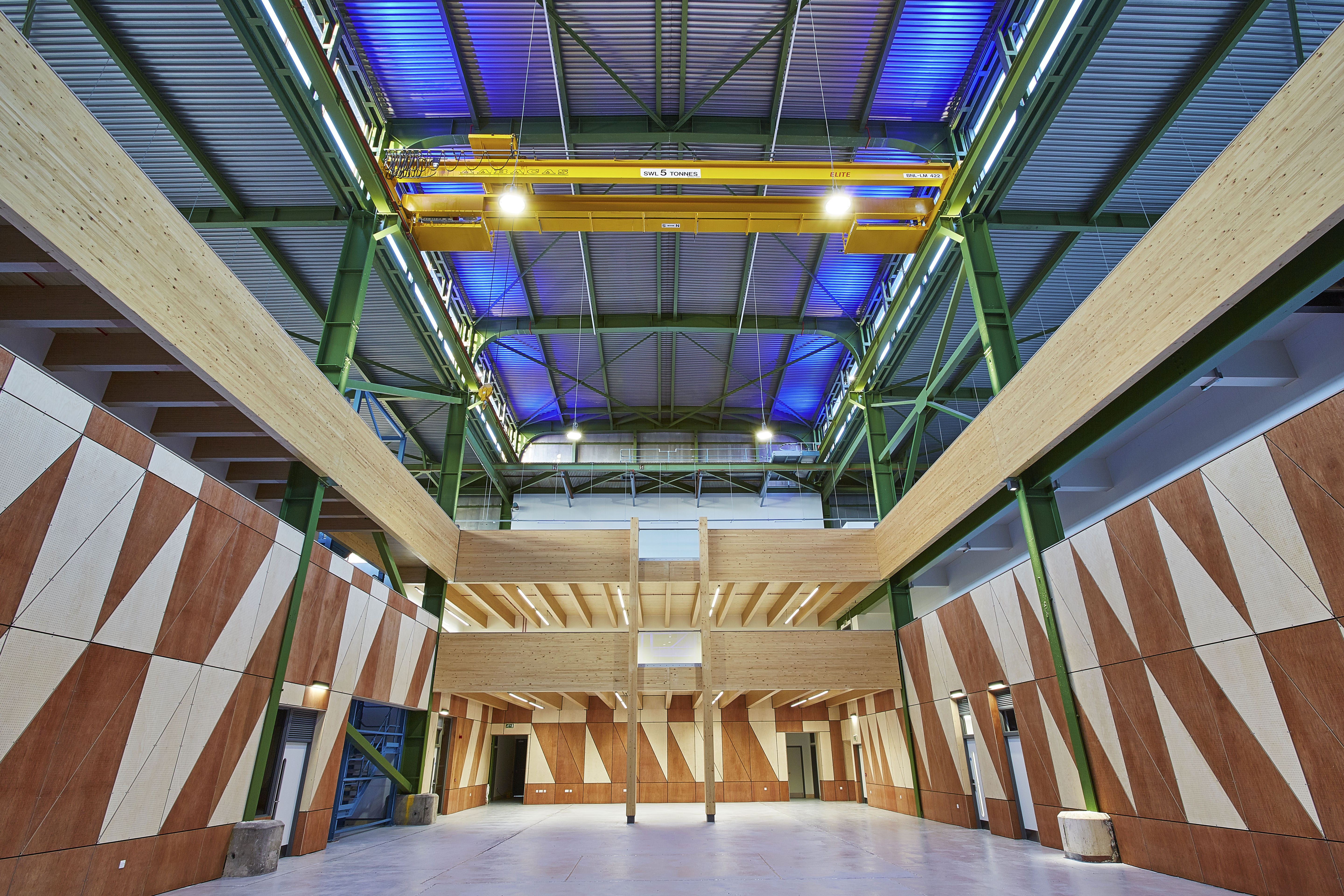 Prefab Offsite Industrial Conversion - yellow crane, blue lights, steel frame, laminated timber structure and plywood cladding.